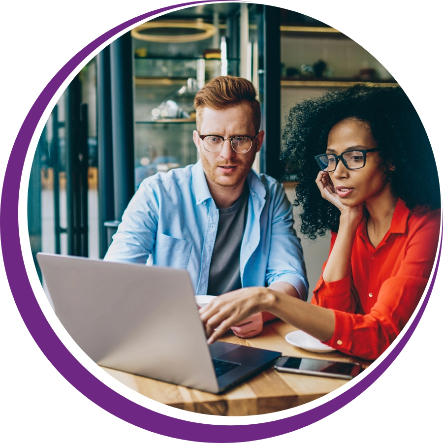 A man and woman sitting at a table with a laptop.